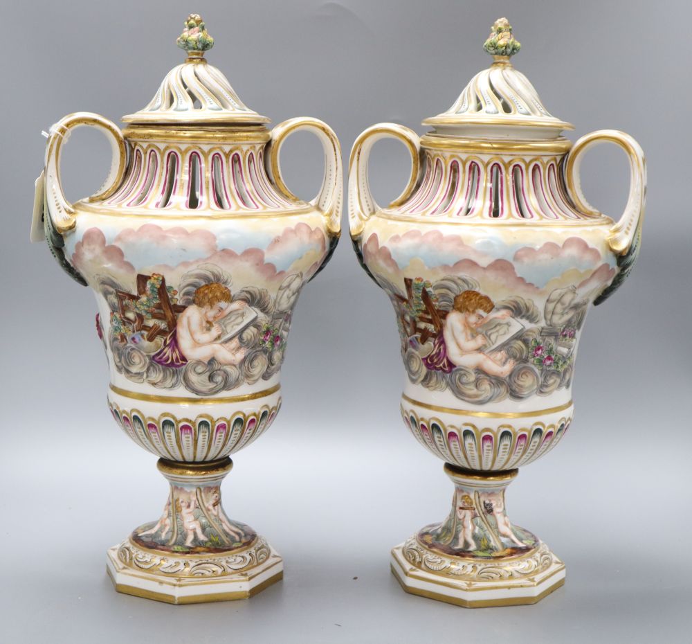 A pair of Ginori Doccia two handled lidded waisted baluster vases, in Capodimonte style moulded in relief with amorini, height 43cm